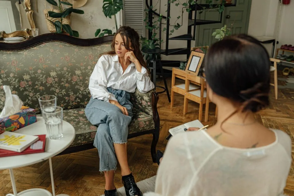A thoughtful counseling session between a psychologist and a patient in a cozy, well-decorated room.